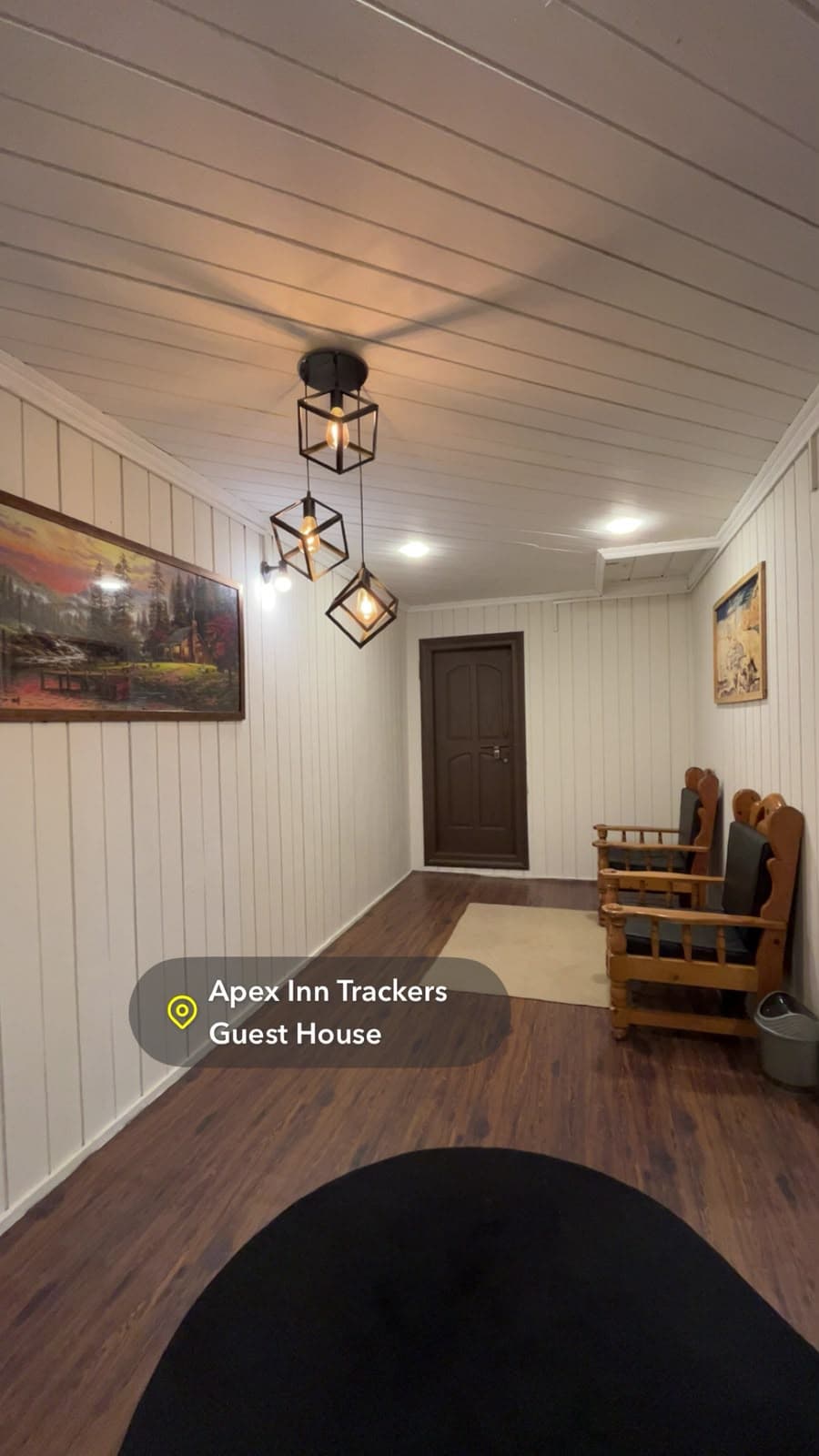 Hallway with pendant lights, artwork and wooden armchairs
