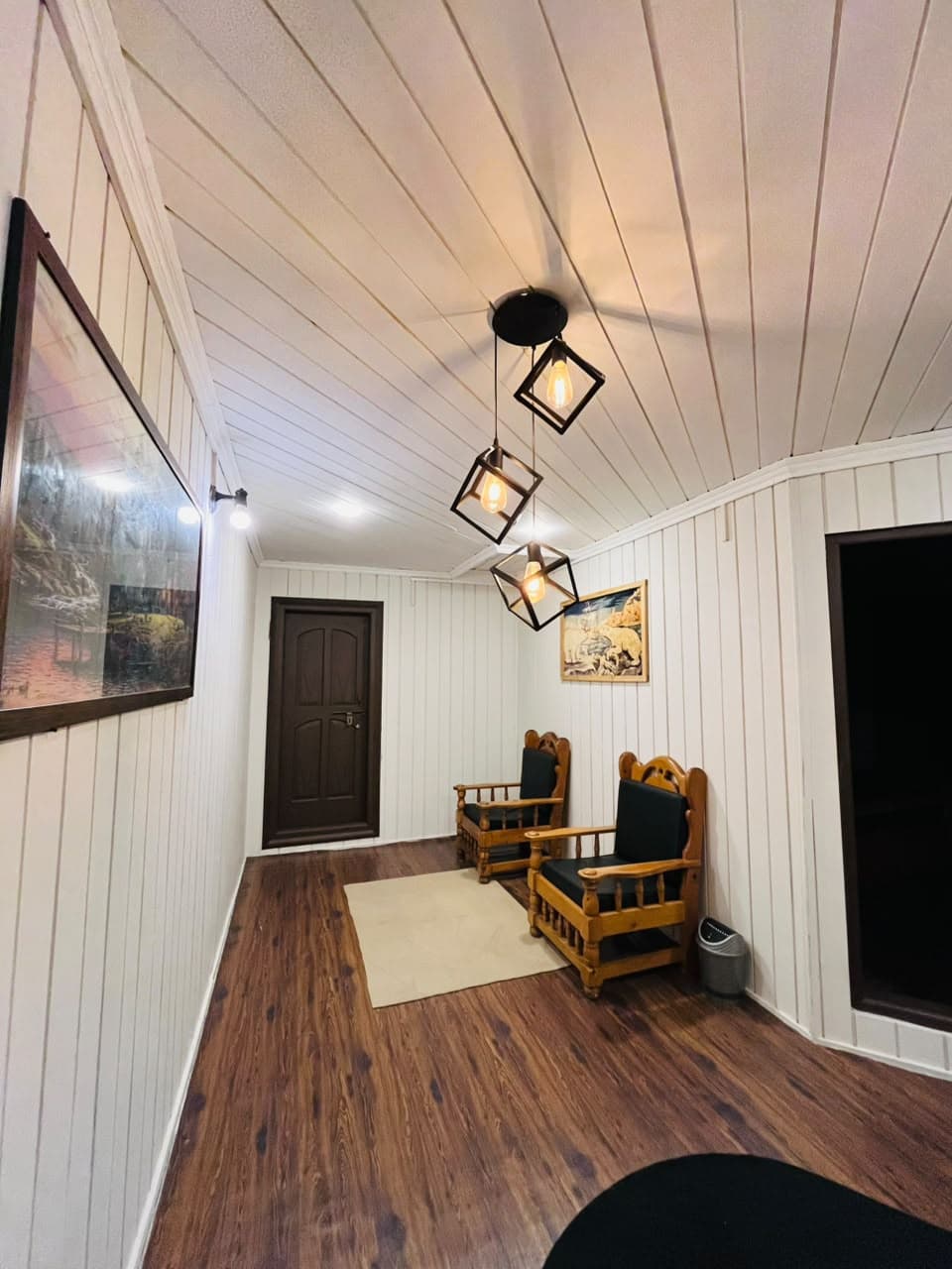 Timber-panelled hallway with pendant lights and a seating corner