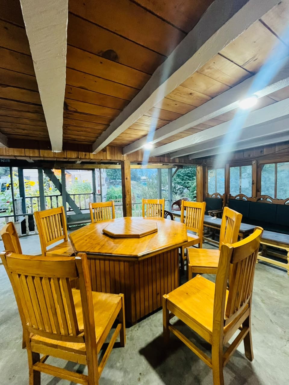 Covered dining hall at Apex Inn with a wooden table, chairs and garden windows