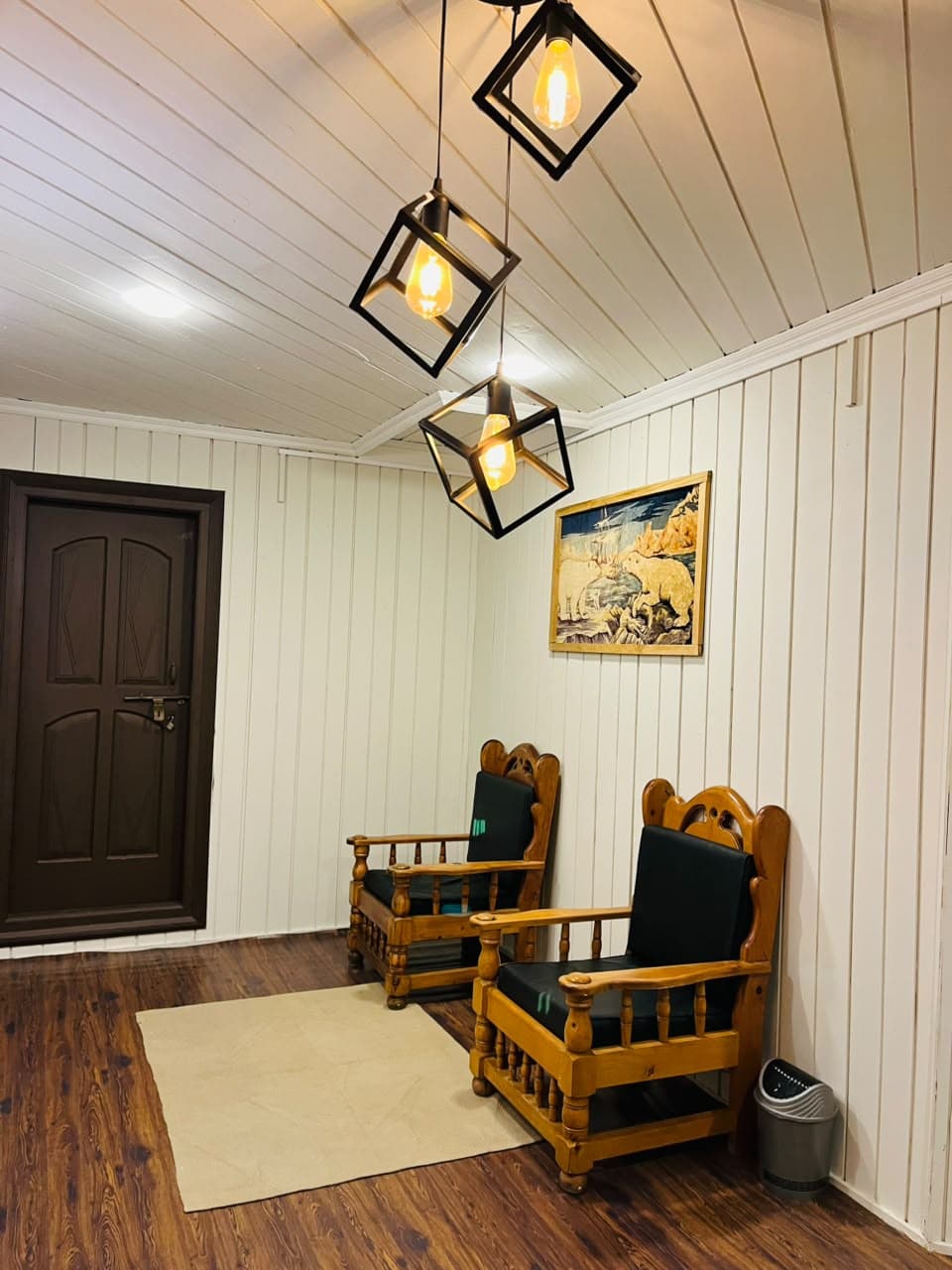 Sitting nook with wooden armchairs under cube pendant lights at Apex Inn