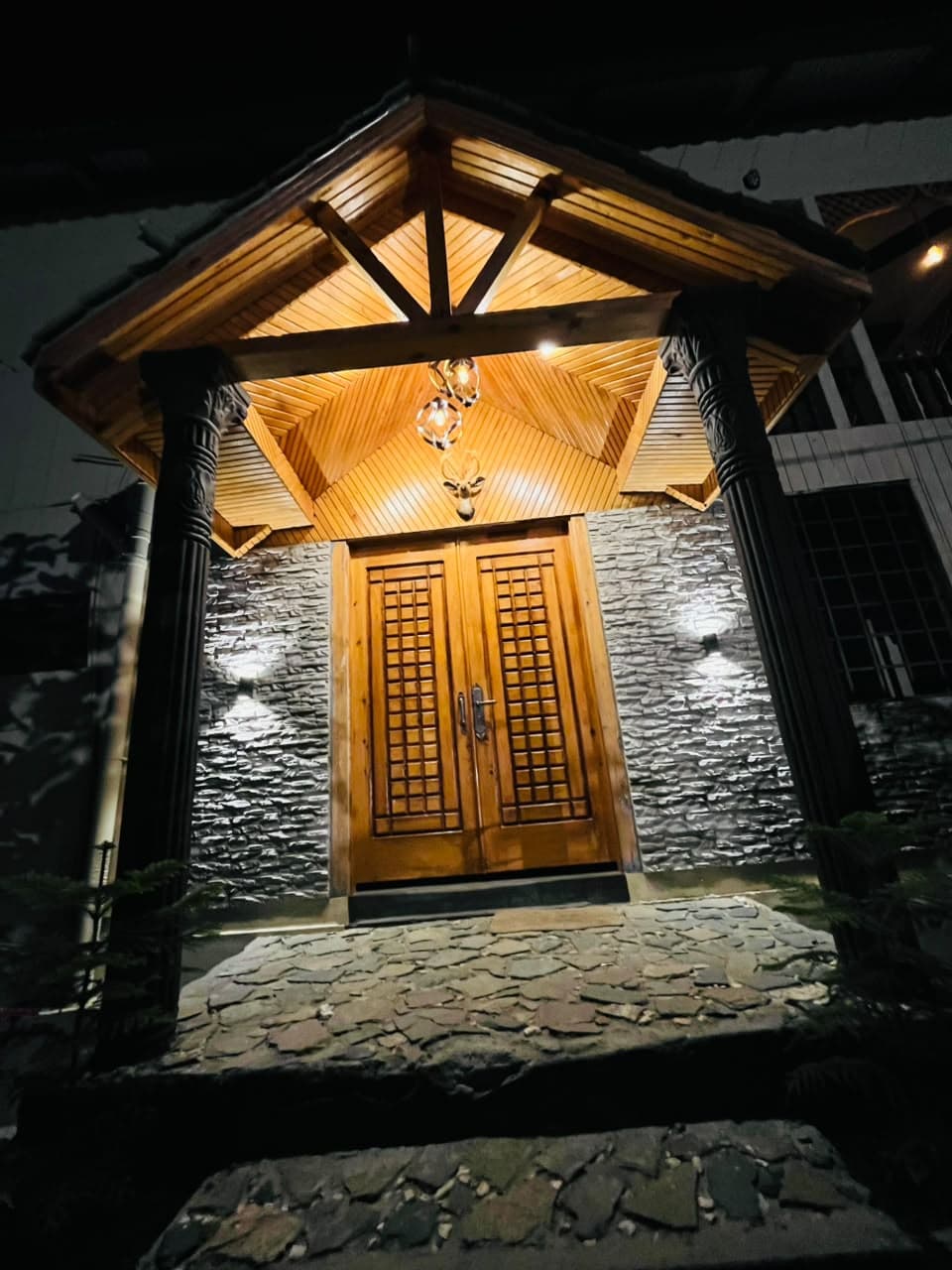 Carved wooden double doors under the lit timber porch at the Apex Inn entrance