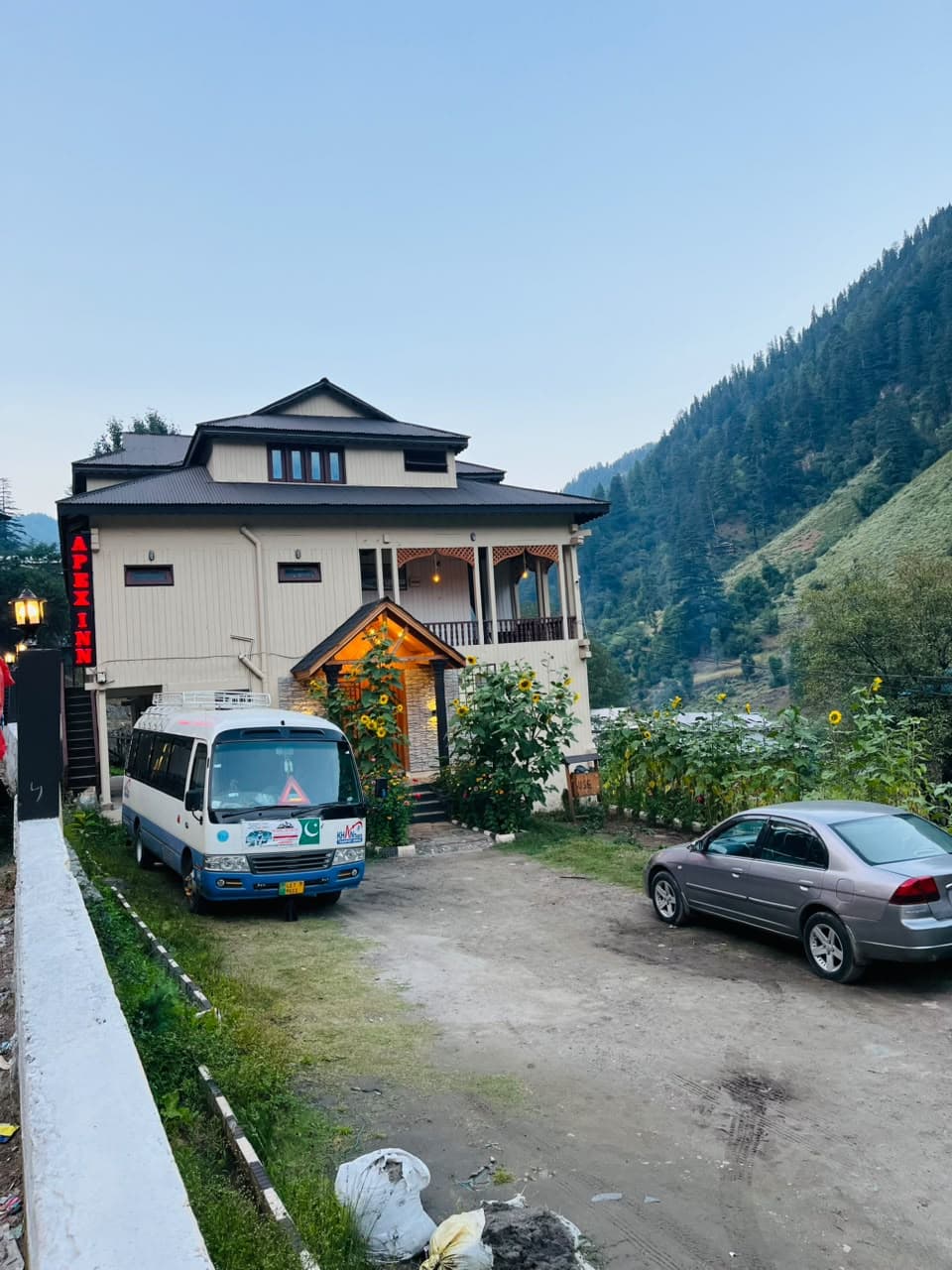Front of Apex Inn at dusk with guest parking and sunflowers