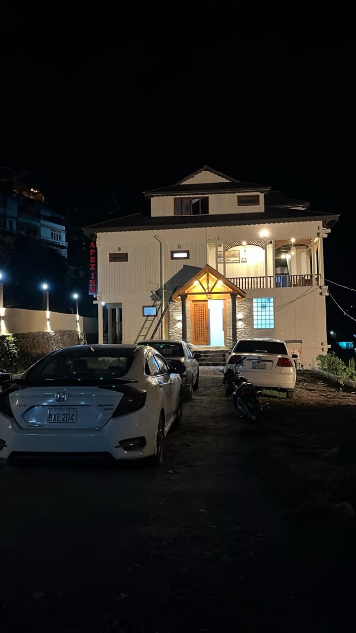 Front of Apex Inn at night with cars parked outside