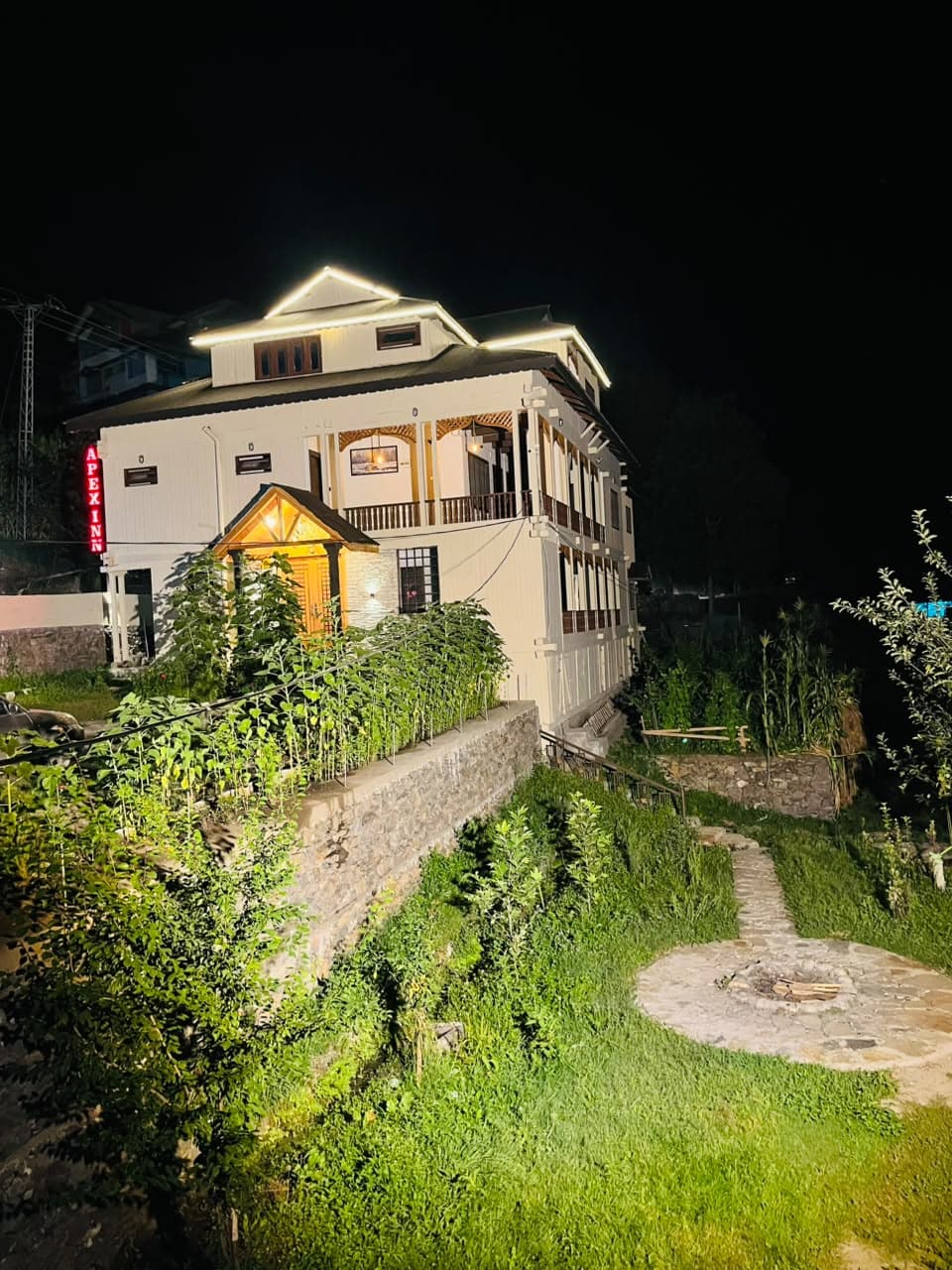 Apex Inn lit up at night above its terraced garden and stone fire pit
