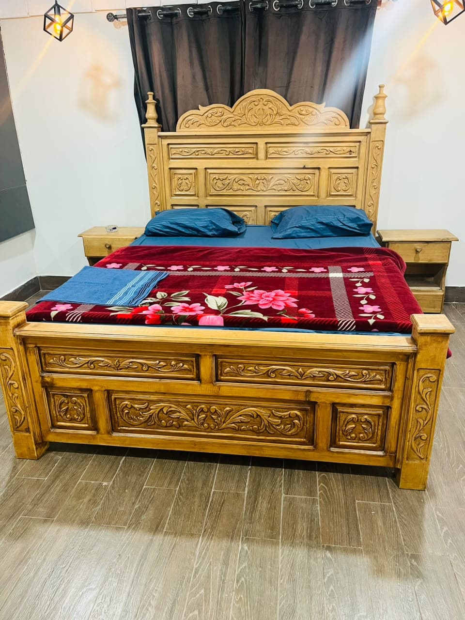 Carved wooden king bed with blue pillows and red blanket