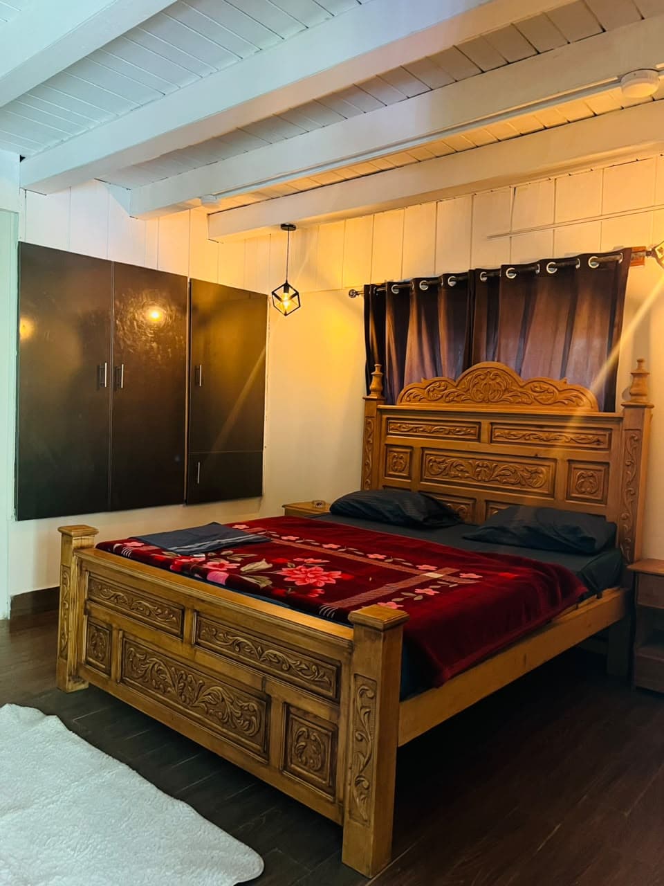 Deluxe Room with a hand-carved wooden king bed under warm lighting