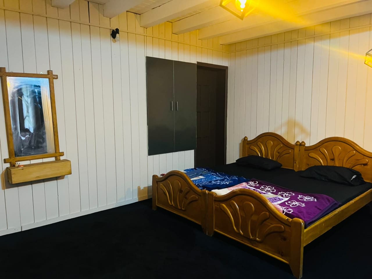 Guest room with carved wooden beds and white timber-panelled walls