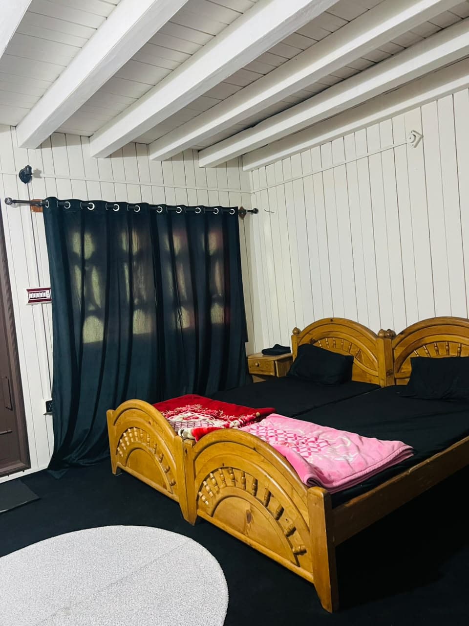 Wooden beds with dark curtains and a carved headboard