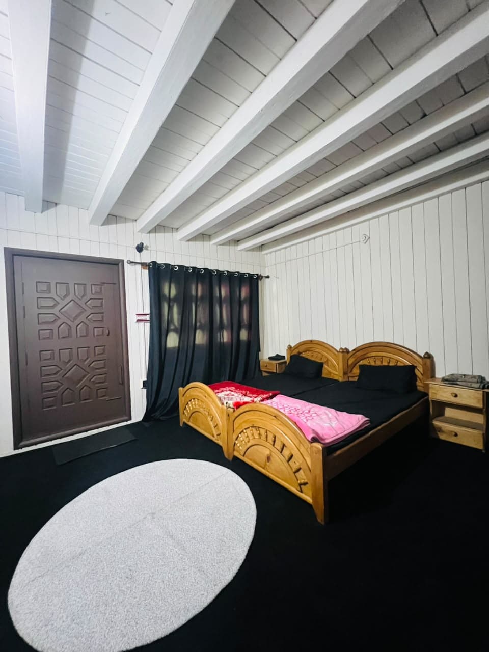 Guest room with a carved wooden door, wooden beds and a round rug