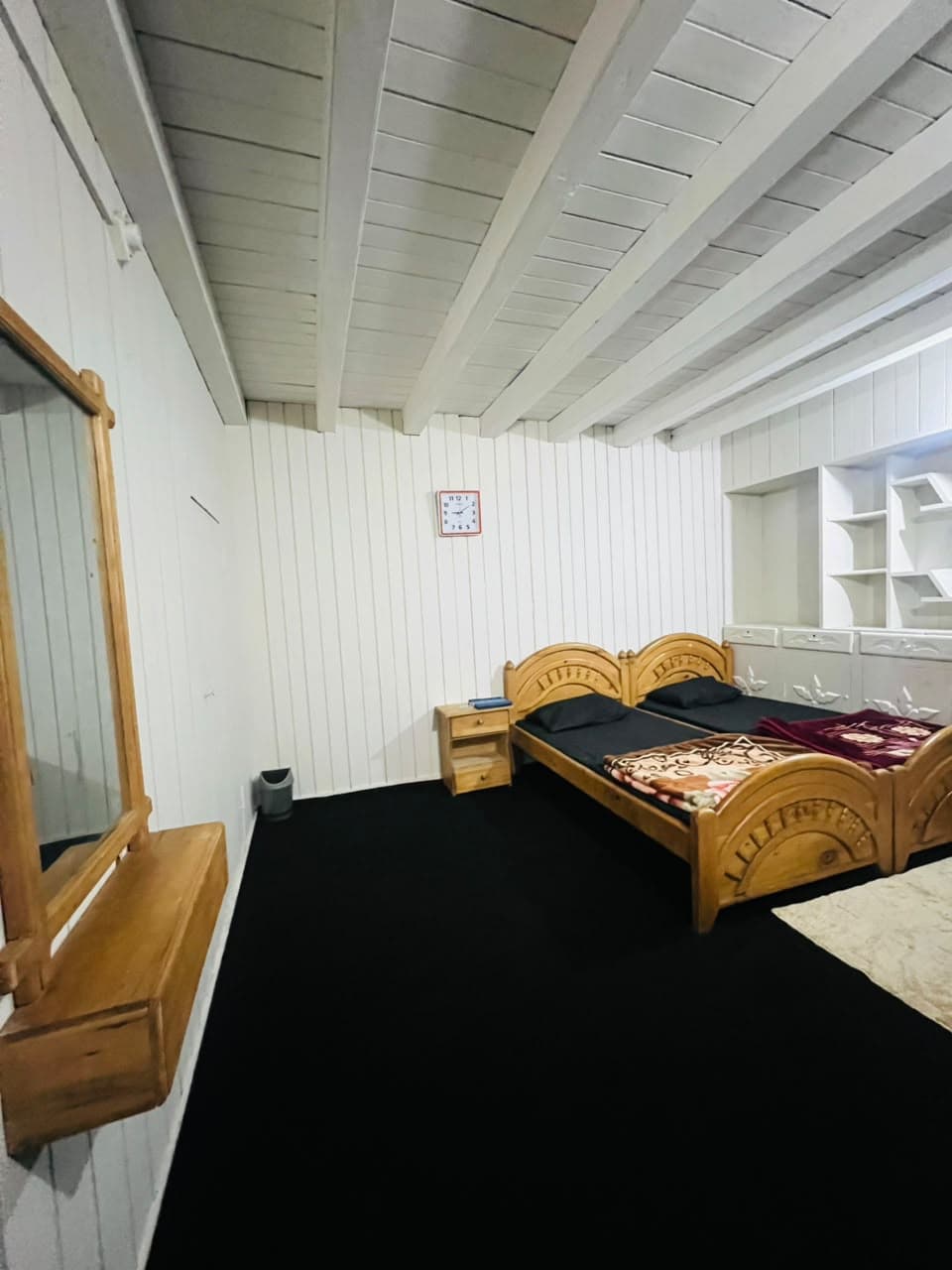 Guest room with wooden beds, wall mirror and open shelves