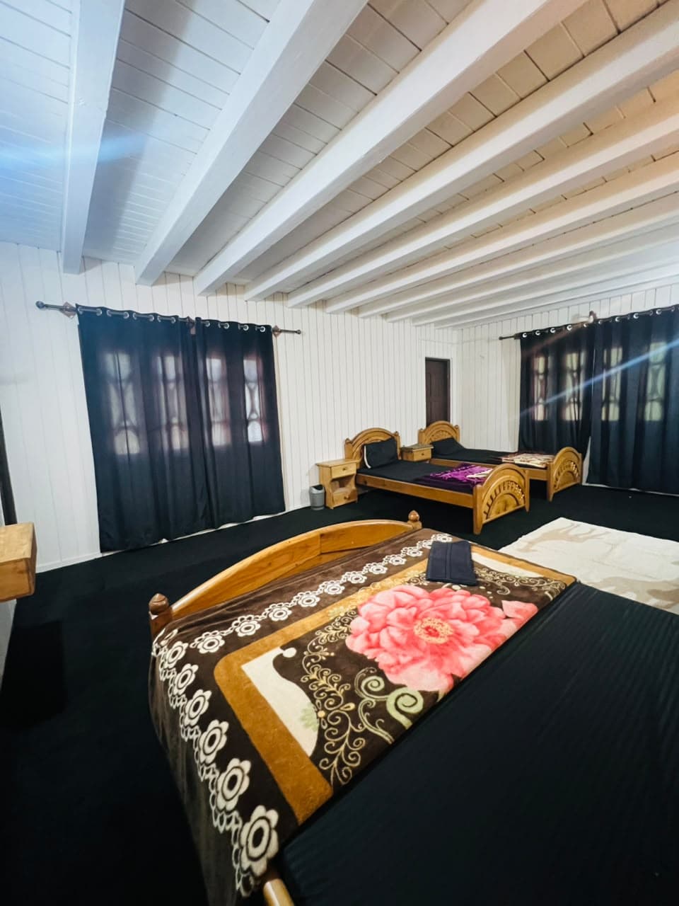 Family room with a patterned bedspread and dark curtains