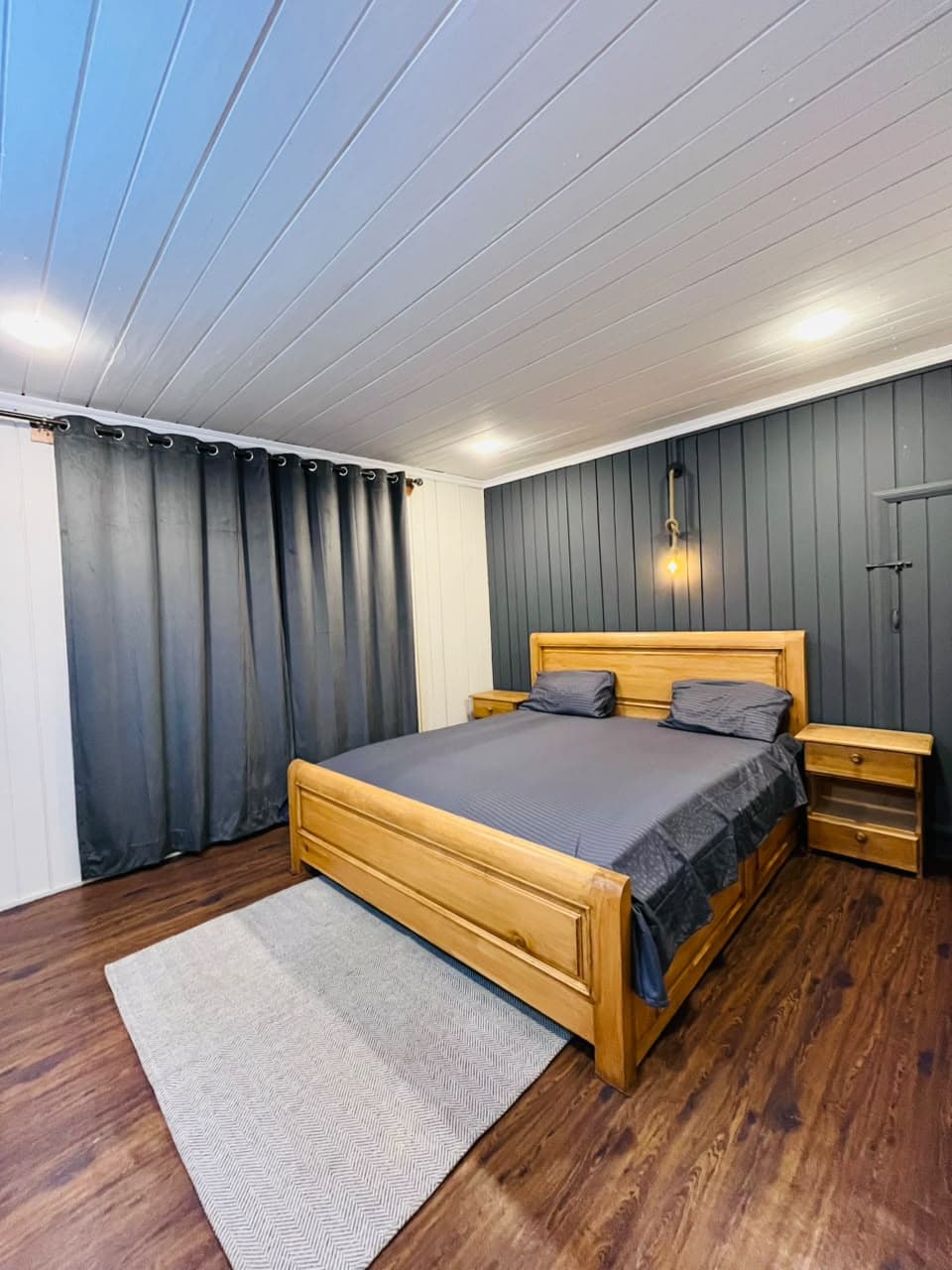 Executive Room with a wooden king bed, grey feature wall and wood floor