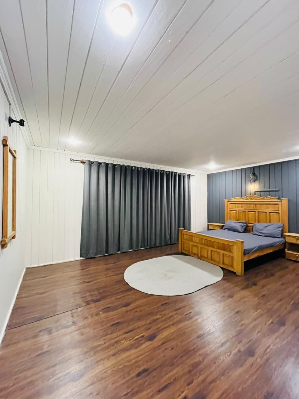 Spacious guest room with floor-length curtains and a round rug