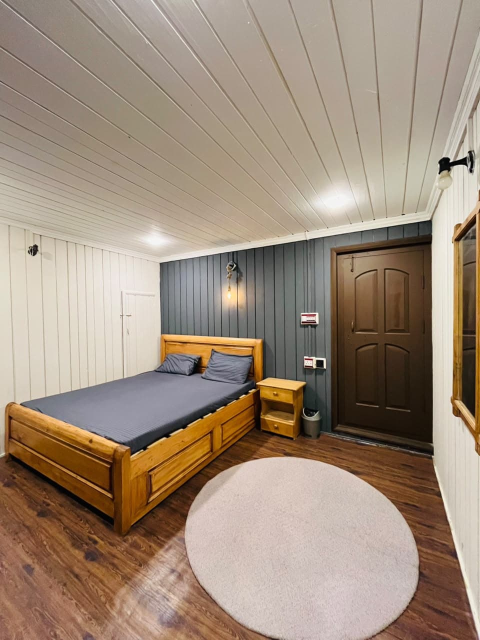 Wooden bed beside a bedside table and wooden door