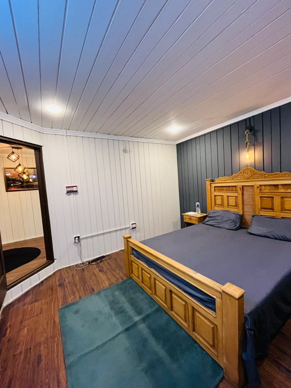 Guest room with a teal rug and wooden king bed