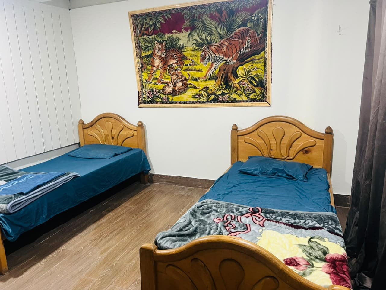 Twin room with two single beds beneath a tiger tapestry