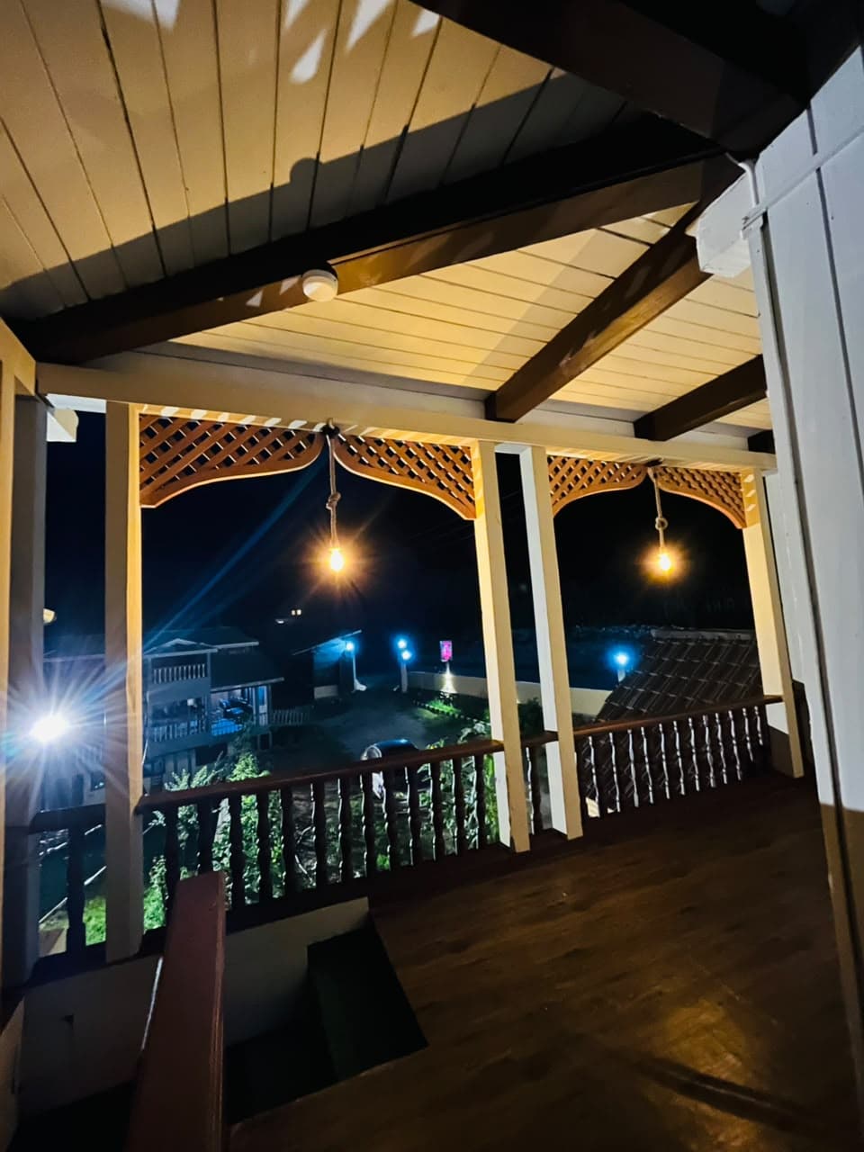 Covered wooden balcony with hanging lights at night