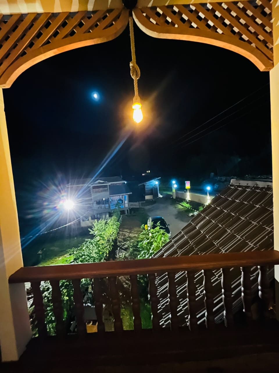 Carved balcony arch with a hanging light and the valley at night