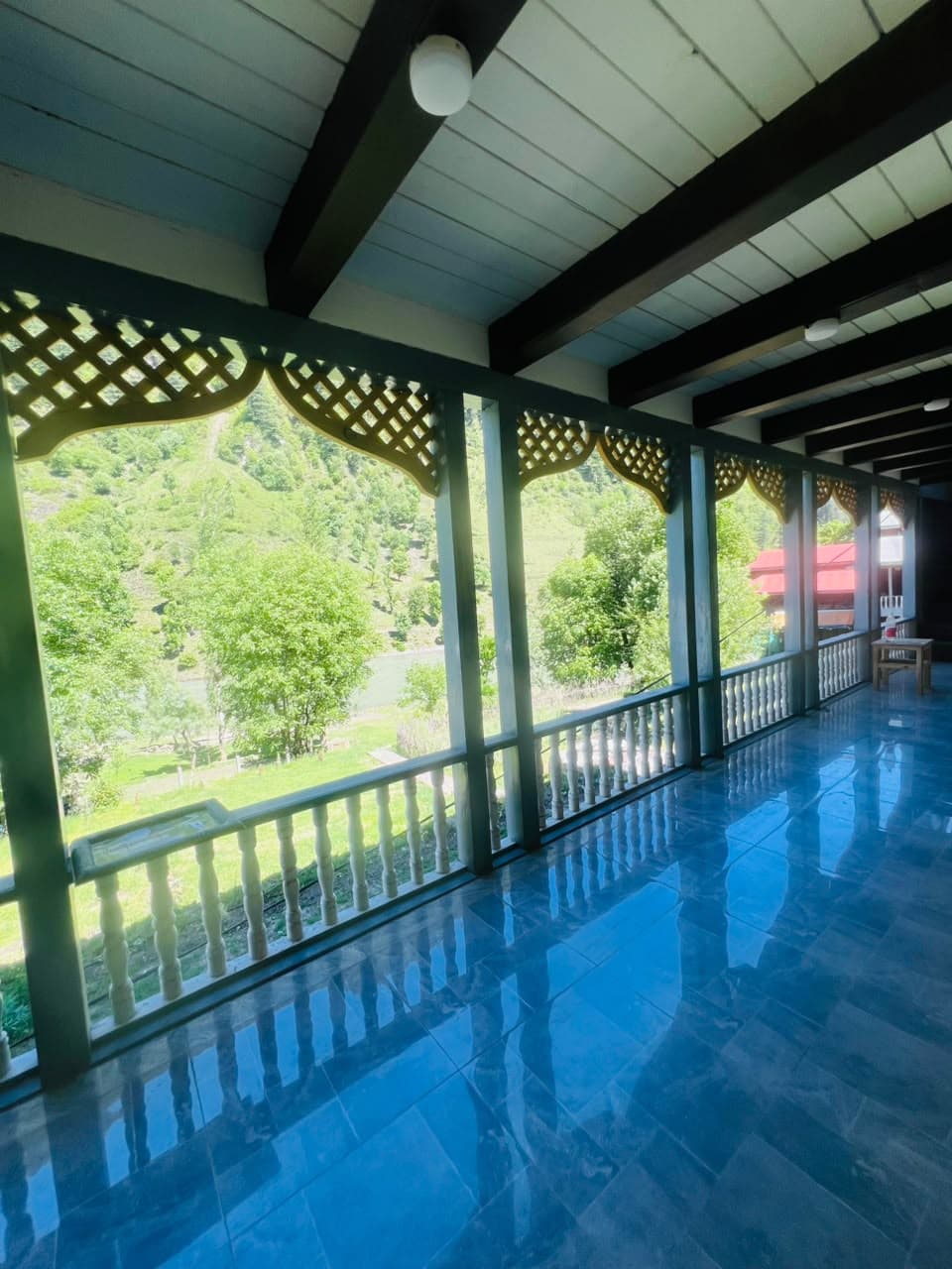 Covered balcony at Apex Inn overlooking green Neelum Valley hills and the river